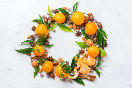 Food and drink, holidays concept. Christmas new year wreath with spices and tangerine on a white rustic table. Copy space top view flat lay backgroundの写真素材