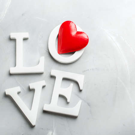 Love and still life concept. Valentines day holiday text with red heart. Copy space trendy background, top view flat layの写真素材