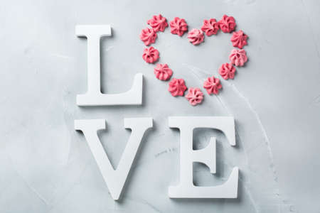 Love and still life concept. Valentines day holiday text with pink meringue heart. Trendy copy space background, top view flat layの写真素材