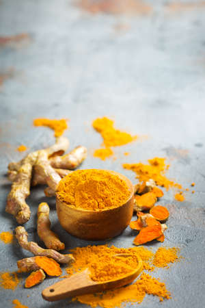 Food and drink, diet nutrition, health care concept. Raw organic orange turmeric root and powder, curcuma longa on a grunge cooking table. Indian oriental low cholesterol spices. Copy space backgroundの写真素材