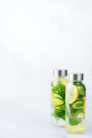 Health care, fitness, healthy nutrition diet concept. Fresh cool lemon cucumber mint infused water, cocktail, detox drink, lemonade in a glass jar for spring summer days. Light copy space backgroundの写真素材