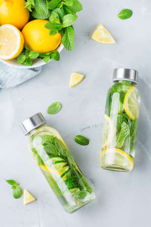 Health care, fitness, healthy nutrition diet concept. Fresh cool lemon cucumber mint infused water, cocktail, detox drink, lemonade in a glass jar. Light top view flat lay backgroundの写真素材