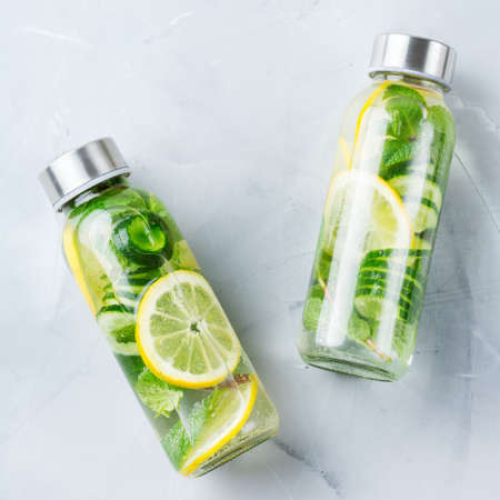 Health care, fitness, healthy nutrition diet concept. Fresh cool lemon cucumber mint infused water, cocktail, detox drink, lemonade in a glass jar. Light top view flat lay backgroundの写真素材