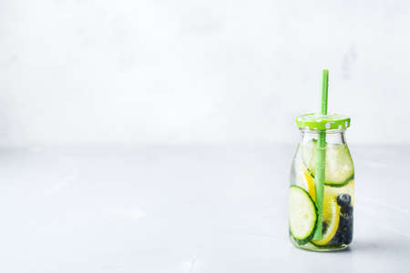 Health care, fitness, healthy nutrition diet concept. Fresh cool lemon cucumber berry infused water, cocktail, detox drink, lemonade in a glass bottle for spring summer days. Copy space backgroundの写真素材