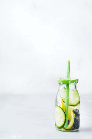 Health care, fitness, healthy nutrition diet concept. Fresh cool lemon cucumber berry infused water, cocktail, detox drink, lemonade in a glass bottle for spring summer days. Copy space backgroundの写真素材