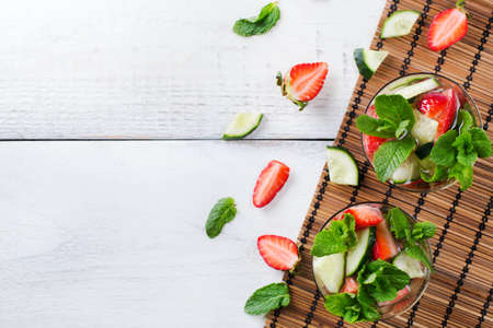Healthcare, fitness, healthy nutrition concept. Fresh cool cucumber strawberry mint infused water, cocktail, detox drink, lemonade for spring summer days. Copy space background, top view flat layの写真素材