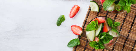 Healthcare, fitness, healthy nutrition concept. Fresh cool cucumber strawberry mint infused water, cocktail, detox drink, lemonade for spring summer days. Copy space background, top view flat layの写真素材