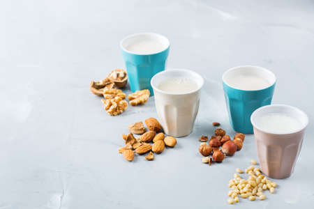 Food and drink, health care, diet and nutrition concept. Assortment of organic vegan non diary milk from nuts in glasses on a kitchen table. Copy space backgroundの写真素材
