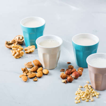 Food and drink, health care, diet and nutrition concept. Assortment of organic vegan non diary milk from nuts in glasses on a kitchen tableの写真素材