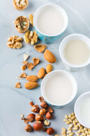 Food and drink, health care, diet and nutrition concept. Assortment of organic vegan non diary milk from nuts in glasses on a kitchen table. Top view flat lay backgroundの写真素材