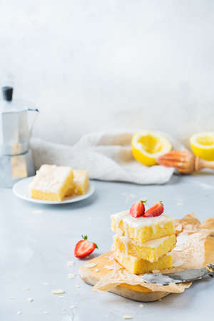 Food, breakfast teatime concept. Homemade lemon polenta cookie bars with white icing on a kitchen table with coffee. Copy space backgroundの写真素材