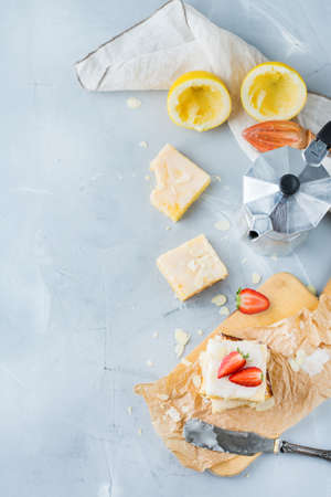 Food, breakfast teatime concept. Homemade lemon polenta cookie bars with white icing on a kitchen table with coffee. Top view flat lay copy space backgroundの写真素材