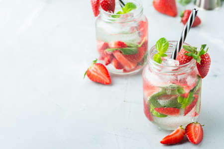 Food and drink, holidays party concept. Cold fresh alcohol beverage mojito cocktail with white rum, soda, red strawberry and basil for refreshment in summer days. Copy space backgroundの写真素材