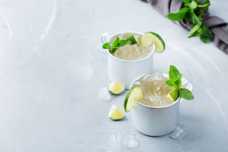 Food and drink, holidays party concept. Cold fresh classic beverage moscow mule cocktail in a silver mug with vodka, ginger beer. lime and mint for refreshment in summer days. Copy space backgroundの写真素材