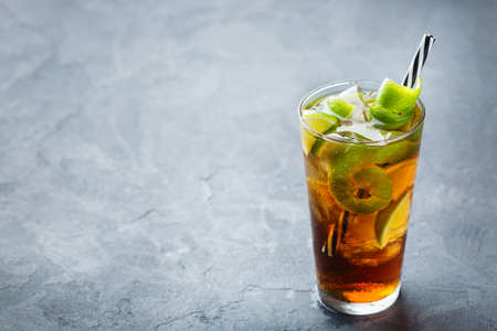 Food and drink, holidays party concept. Alcohol cocktail with rum and cola cuba libre beverage, longdrink in a glass with straw, ice and lime zest on a dark table. Copy space top view backgroundの写真素材