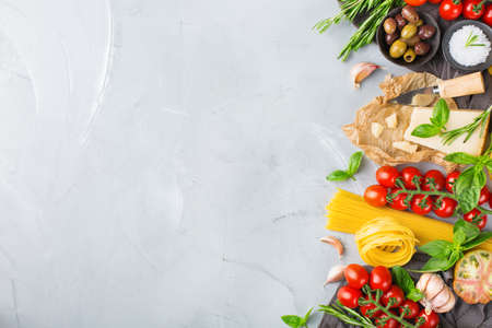 Italian food ingredients cooking background with pasta, olive oil, parmesan cheese, green basil, ripe tomatoes, garlic, herbs. Copy space flat lay top view backgroundの写真素材