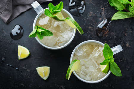 Food and drink, holidays party concept. Cold fresh classic beverage moscow mule cocktail in a silver mug with vodka, ginger beer. lime and mint for refreshment in summer days. Top viewの写真素材