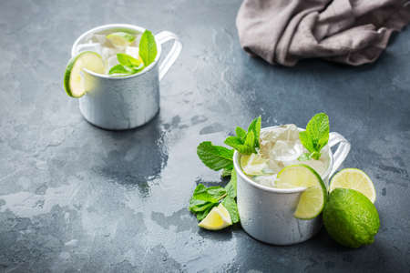 Food and drink, holidays party concept. Cold fresh classic beverage moscow mule cocktail in a silver mug with vodka, ginger beer. lime and mint for refreshment in summer daysの写真素材