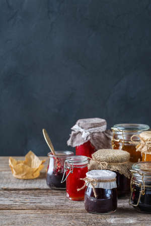Food and drink, harvest summer autumn concept. Assortment of seasonal berries and fruits jams in jars on a wooden table. Copy space rustic backgroundの写真素材