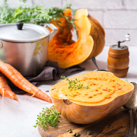 Food and drink, still life, diet and nutrition concept. Seasonal fall autumn roasted orange pumpkin butternut squash carrot soup with ingredients on a table. Cozy kitchen backgroundの写真素材