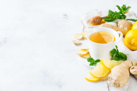 Food and drink, still life health care concept. Ginger tea infusion beverage in white cup with lemon mint honey on a kitchen table for cold and flu winter autumn days. Copy space backgroundの写真素材