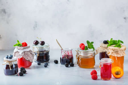 Food and drink, harvest summer autumn concept. Assortment of seasonal berries and fruits jams in jars on a wooden table. Copy space rustic backgroundの写真素材