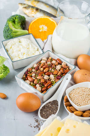 Balanced diet nutrition, healthy eating concept. Assortment of food sources rich in calcium, beans, dairy products, sardines, broccoli, chia seeds, almonds on a kitchen tableの写真素材