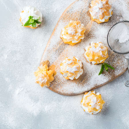 Food and drink, holidays concept. Delicious sweet homemade profiteroles with cream on a modern kitchen tableの写真素材