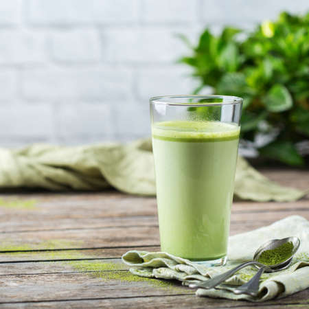 Healthy clean eating concept, breakfast morning table. Glass of trendy matcha green tea latte on a wooden table. Cozy cafe atmosphereの写真素材