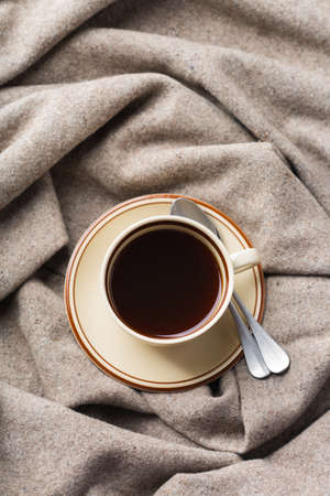 Autumn, fall, winter home decor in scandinavian, hygge style. Seasonal composition with cup of coffee, warm woolen scarf, soft plaid on a rustic wooden table. Flat lay backgroundの写真素材