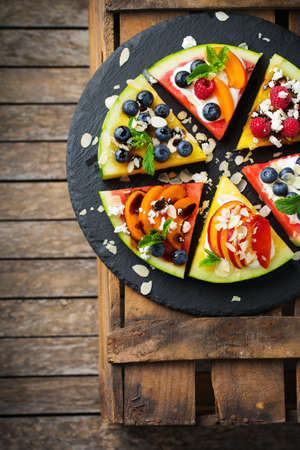 Healthy clean eating, dieting and nutrition, seasonal, summer concept. Watermelon pizza with berries, fruits, yogurt, feta cheese on a rustic wooden table. Top view flat lay copy space background.の写真素材