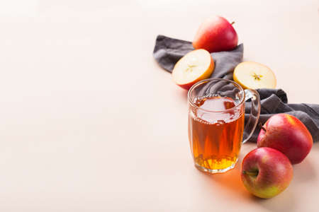 Food and drink, harvest autumn fall concept. Fresh organic apple juice in a mug with ripe fruits on trendy pink coral background. Copy spaceの写真素材