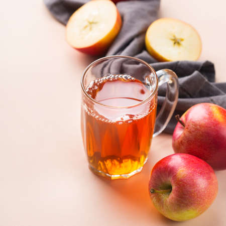 Food and drink, harvest autumn fall concept. Fresh organic apple juice in a mug with ripe fruits on trendy pink coral backgroundの写真素材