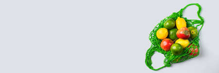 Textile mesh bag with produce, fruits and vegetables. Zero waste, eco-friendly, plastic free recycled, reusable concept. Copy space, flat lay bleached coral background, banner の写真素材