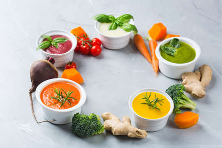 Healthy food, clean eating concept. Variety of colorful seasonal fall vegetables creamy soups with ingredients. Pumpkin, broccoli, carrot, beetroot, potato, tomato spinachの写真素材