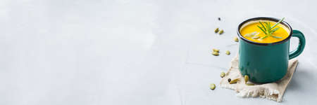 Healthy food, clean eating concept. Seasonal spicy fall vegetables creamy pumpkin and carrot soup with ingredients on a table. Copy space background, bannerの写真素材