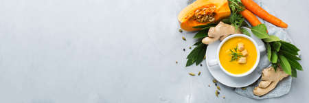 Healthy food, clean eating concept. Seasonal spicy fall vegetables creamy pumpkin and carrot soup with ingredients on a table. Flat lay, copy space background, bannerの写真素材