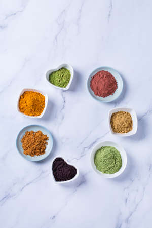 Balanced nutrition concept for clean eating antioxidant detox diet. Assortment of superfood powder - acai, turmeric, wheat, ginger, cinnamon, matcha. Flat lay, copy space marble backgroundの写真素材