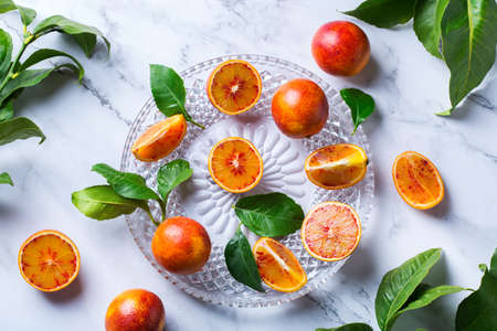 Vitamin, clean eating, healthy food vegan concept. Whole and sliced sweet sicilian blood oranges on a white marble table. Top view flat lay backgroundの写真素材