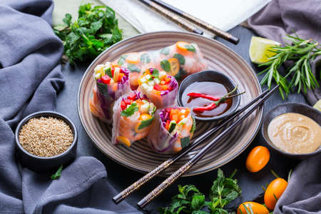 Spring or summer rolls with rice paper, carrot, chili sauce, red cabbage, zucchini , pepper, shrimps and kumquats. Tasty asian food.の写真素材