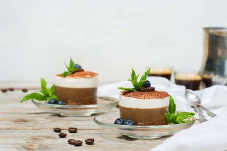 Homemade small mini coffee and chocolate cheesecake with blueberries and mint leaves on a plate 