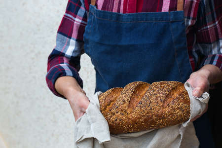 Mature senior woman holding freshly baked loaf of homemade rye bread in her handsの写真素材