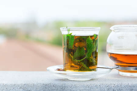 Drink for stress, anxiety, chronic fatigue, depression relieving and relaxation. Glass of hot mint tea with cane sugar, traditional Middle East, moroccan, arabic, moorish beverage.の写真素材