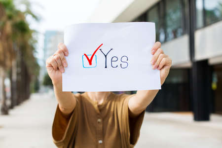 Young woman, activist calls to vote holding in hands paper with statement YES. Political activism, election process, active life positions concept. President, constitution elections.の写真素材