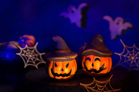 Halloween composition with pumpkins, spider webs and ghosts in the moody dark room. Creative scary decorated greeting card. Lifestyle holidays concept.の写真素材