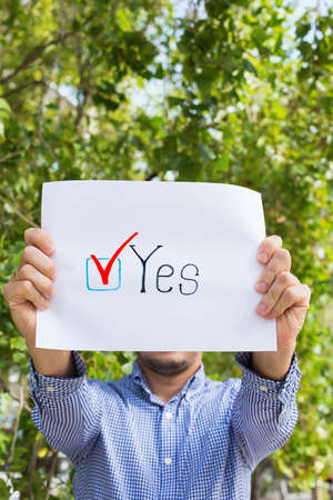 Young man, activist calls to vote holding in hands paper with statement YES. Political activism,...
