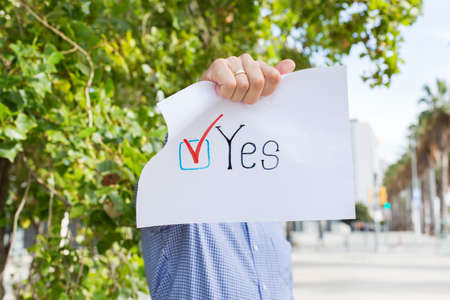 Young man, activist calls to vote holding in hands paper with statement YES. Political activism,...