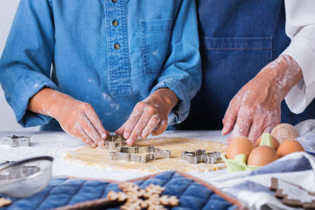 Happy senior mature woman, grandmother and young boy, grandson cooking, kneading dough, baking pie,...