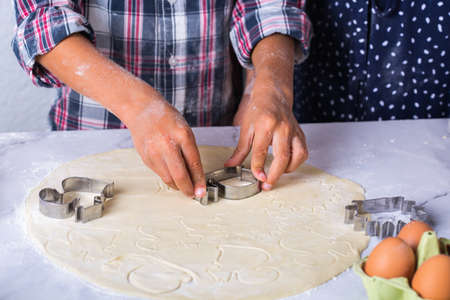 Happy senior mature woman, grandmother and young boy, grandson cooking, kneading dough, baking pie, cake,  cookies. Family time in the cozy kitchen. Autumn activity at home.の写真素材