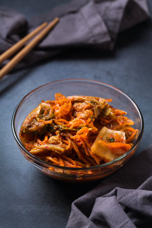 Homemade organic traditional korean kimchi cabbage salad with chopsticks on a dark table. Fermented vegetarian, vegan preserved gut health food conceptの写真素材